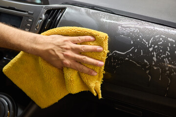 A detailed process of cleaning a car using a yellow cloth for optimal cleanliness and shine