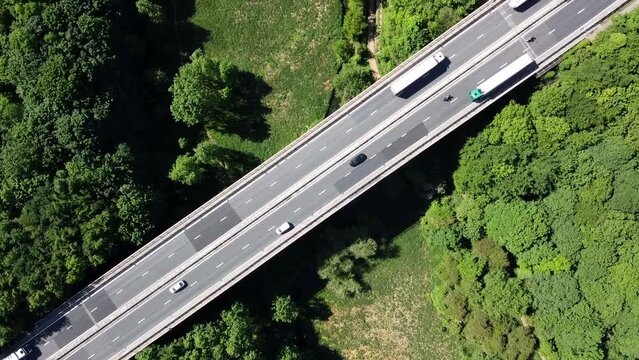 Aerial view of car driving along the dual carriageway road through green meadows landscape on sunny day near Wentbridge West Yorkshire UK. Drone chasing a car.