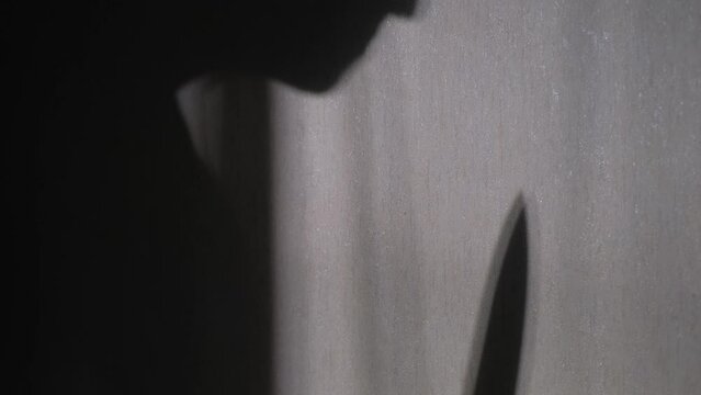 Silhouette of a man with a knife on the wall, close-up