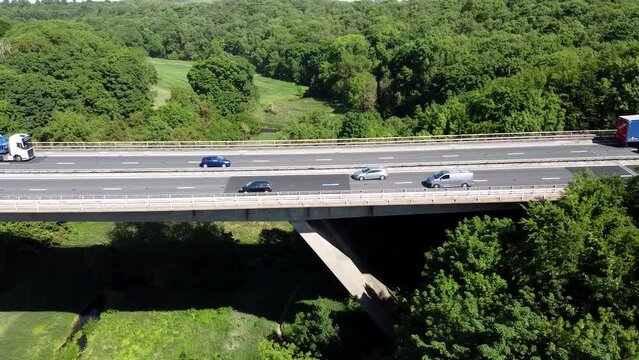 Aerial view of car driving along the dual carriageway road through green meadows landscape on sunny day near Wentbridge West Yorkshire UK. Drone chasing a car.