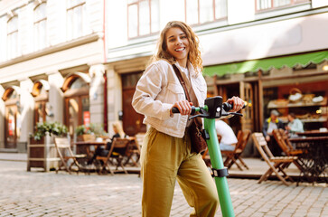 Happy woman rides an electric scooter at weekend leisure time. Ecological transport. Active...