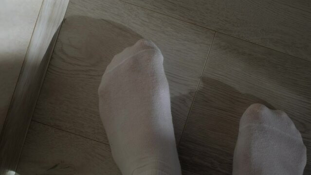 A man checks the cleanliness of the floor with his foot in a white sock, close-up