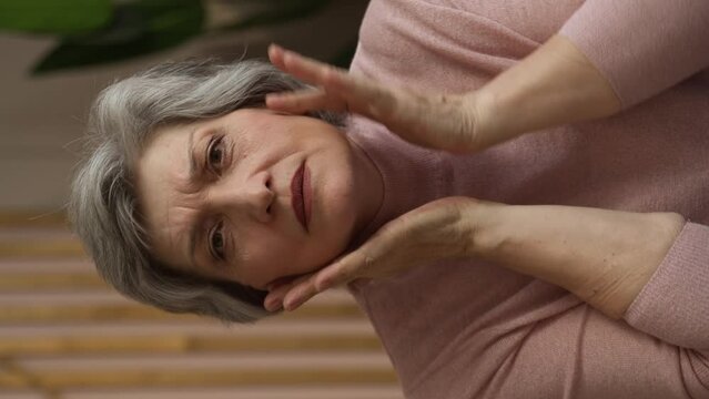 Vertical Screen: A close-up portrait of a gorgeous, beautiful middle-aged woman, 60 years old, touching her smooth, healthy skin. The concept of anti-aging, skin care, cosmetics, spa, body care