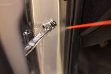 Applying spray lubricant to car door hinges helps keep them functioning smoothly