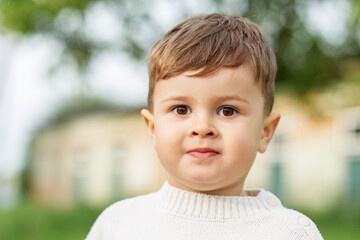 Portrait of curious toddler outdoors. Face.