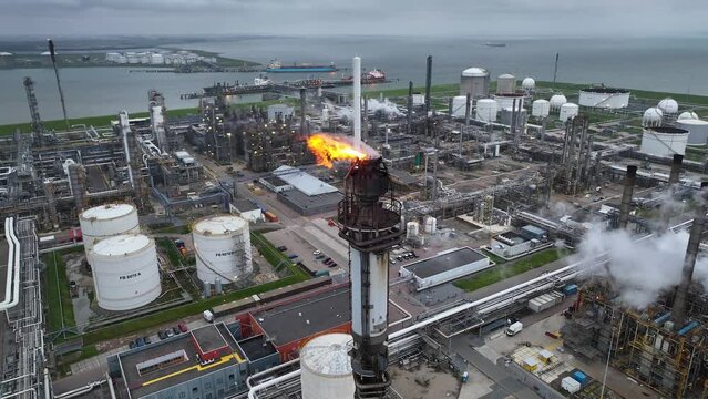 Aerial view of a chemical plant at sunset. Drone shot. Curling fire and cumin smoke filling the sky. Smoking chimneys from the factory. Chimneys of an oil refinery at sunrise pollute the environment