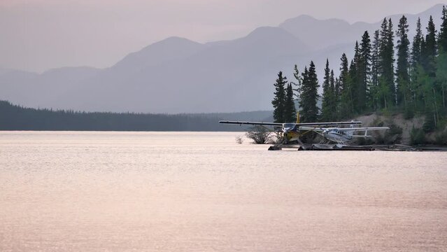Bush planes parked on the lake shore along the Alaska Highway. Flightseeing tours by seaplanes in North America