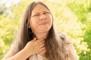 Naklejka premium close-up mature female neck, patient holding affected area, experiencing throat pain, Health concern, loss of voice, tonsillitis