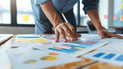Fototapeta premium A businessman reviews a spread of business charts on a desk.