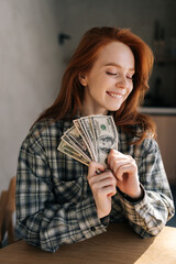 Vertical portrait of happy excited successful young student female holding money dollar bills in...