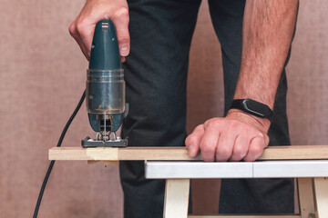 A worker cuts a board with a jigsaw