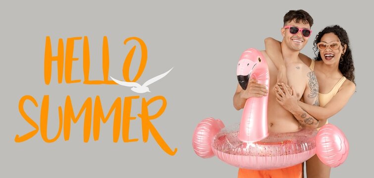 Happy young couple with inflatable ring in shape of flamingo on grey background. Hello, summer