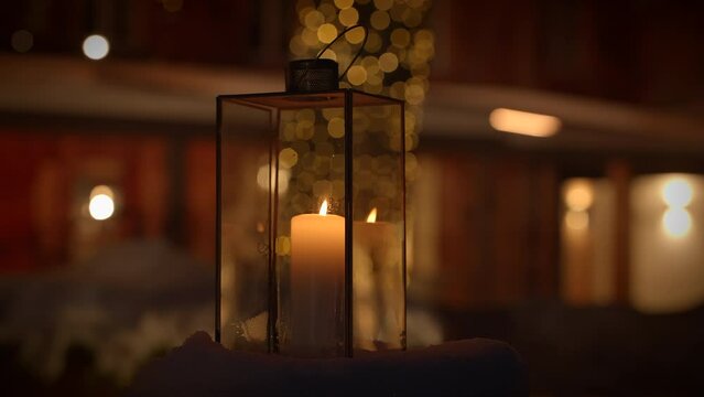 Experience a cozy ambiance with a candle lantern and bokeh lights on a peaceful winter evening