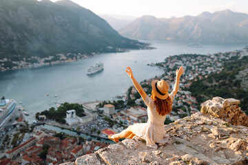 Back view of Tourist woman  standing on the observation deck admiring view of colorful the view of the city. Europe travel. Lifestyle, vacation, rest, active life.