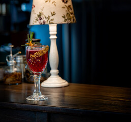 Photograph of a red fruit cocktail with tequila in a glass glass, on a dark wooden table with a...