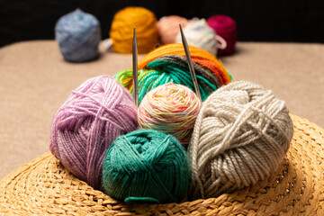 hilos, agujas crochet junto a ovillos de lana en una cesta