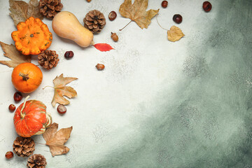 Fresh pumpkins with cones, chestnuts, acorns and autumn leaves on grunge background