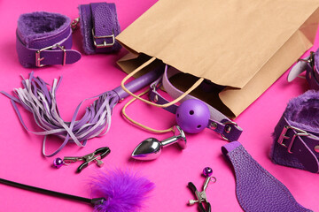 Shopping bag with sex toys on pink background, closeup
