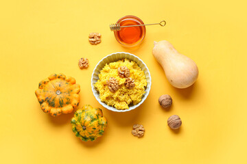 Bowl of tasty millet porridge with pumpkin and ingredients on orange background