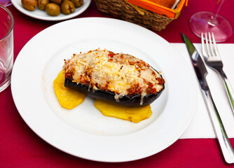 Image of a appetizing stuffed eggplant with cheese baked on top, served on chopped potatoes