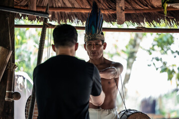 Indigenous Wayuri tribe member presents shamanic drum to tourist in Ecuadorian jungle