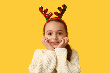 Cute little girl in reindeer horns on yellow background © Pixel-Shot