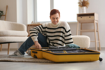 Young man packing suitcase for journey at home