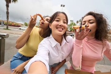 Naklejka premium Three women are eating pizza and smiling