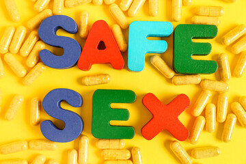 Colorful letters with text SAFE SEX and pills on yellow background