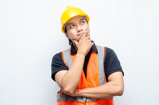 Title	
young asian man construction worker using yellow helmet and orange vest makes a thinking gesture. asian male worker in pensive expression while thinking looking for idea.