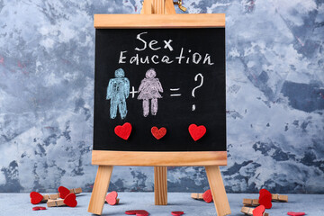 Chalkboard with drawn figures of couple and written text SEX EDUCATION on grunge background
