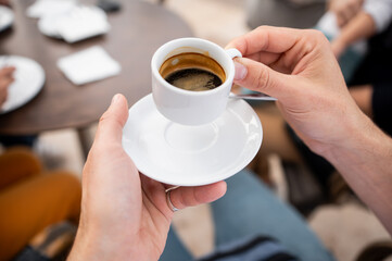 Close-up of hands holding cup of freshly brewed espresso coffee