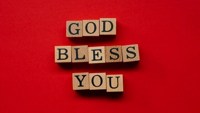 a red warm background without shadows the male hand laid wooden cubes with colored words laid out the god bless you