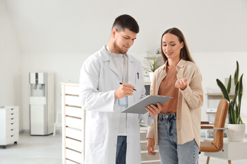 Obraz premium Male receptionist with clipboard and patient in clinic