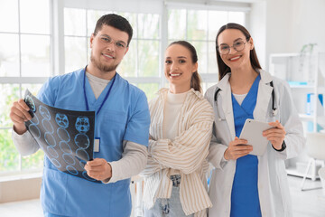 Obraz premium Smiling doctors with MRI scan and patient in clinic