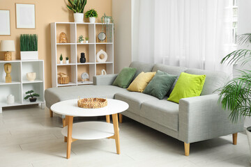 Stylish living room with comfortable sofa, coffee table, shelving units and curtains