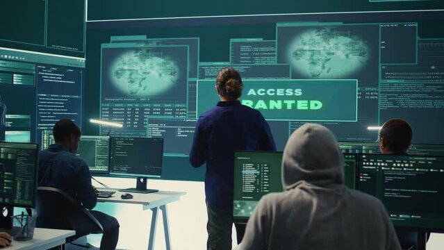 Group of professional hackers gaining access into government database to steal important information for hybrid warfare. Experts work on scams and phishing activity in high tech office. Camera B.