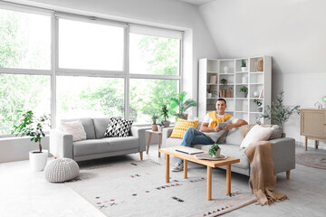 Young man sitting on grey sofa at home