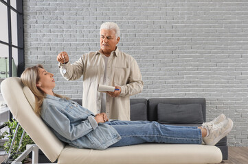 Male psychologist with pocket watch hypnotizing woman in office