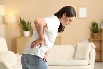 Young woman suffering from back pain at home