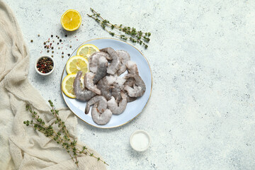 Plate with fresh raw shrimps and lemon on white background