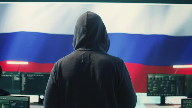 Expert in governmental hacking room with a Russian flag on big screen, individual in cyberwarfare and propaganda. Russian federation hacker works on sabotage and political manipulation. Camera B.