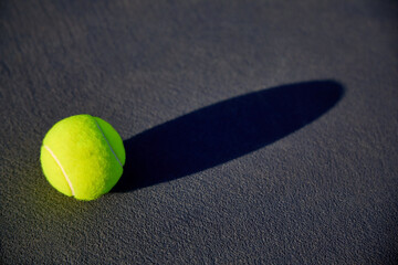 A tennis ball on tennis court with court lines and shadows
