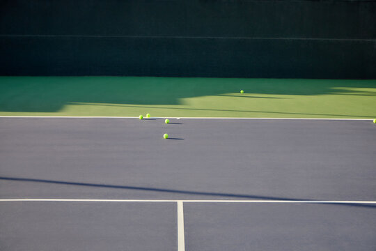 A tennis ball on tennis court with court lines and shadows
