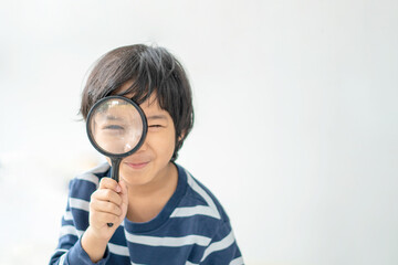Education and back to school concept. Happy little kindergarten child boy holding magnifying glass and read a book on the floor. Preschool children kids enjoy and fun study and doing homework at home. © CandyRetriever 