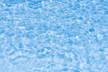 Blue water with ripples on the surface. Defocus blurred transparent blue colored clear calm water surface texture with splashes and bubbles. Water waves with shining pattern texture background.