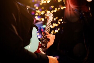 A guitarist plays a chord on the fretboard during a band's performance. Close-up, soft lights on...