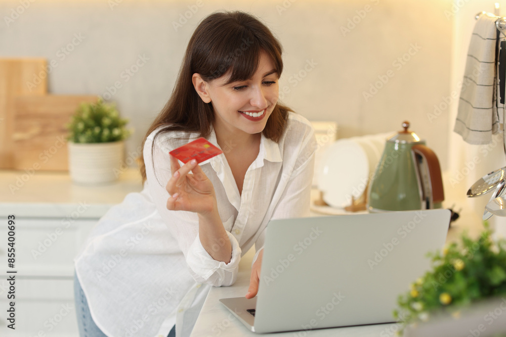 Canvas Prints Online banking. Smiling woman with credit card and laptop paying purchase in kitchen