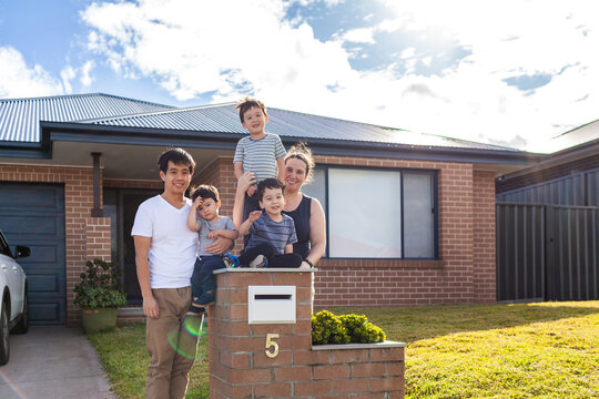 portrait of mixed race Chinese Australian family outside home with kids sitting on mailbox