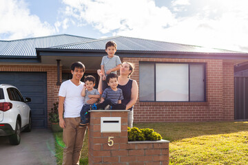 portrait of mixed race Chinese Australian family outside home with kids sitting on mailbox